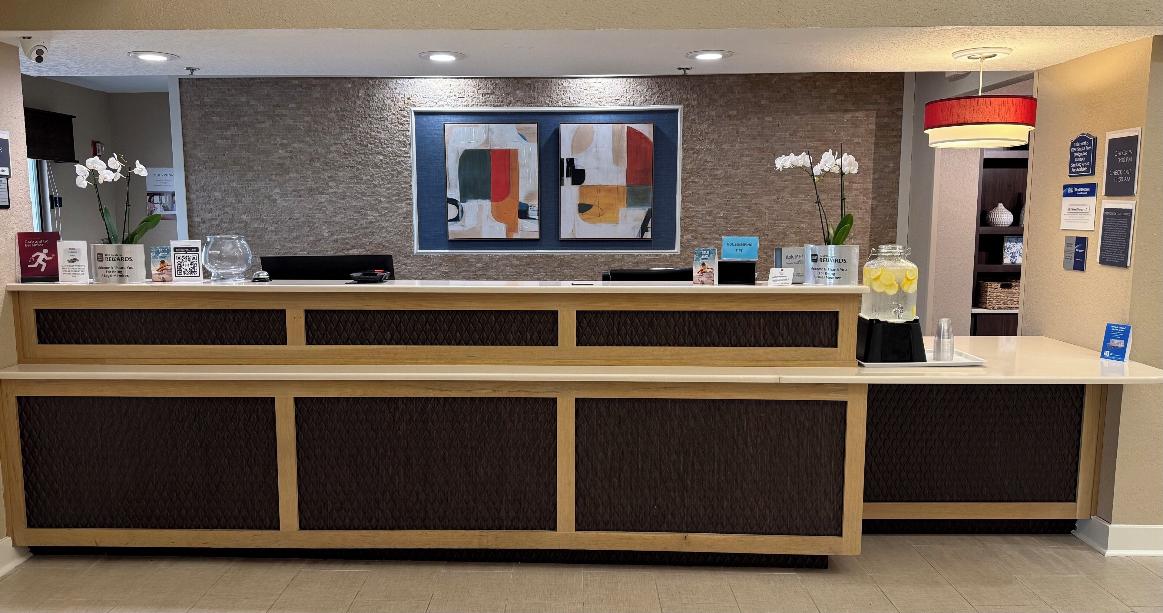A reception desk with a modern design, including a large abstract painting above it and a sign indicating a 300-450 room check-in.