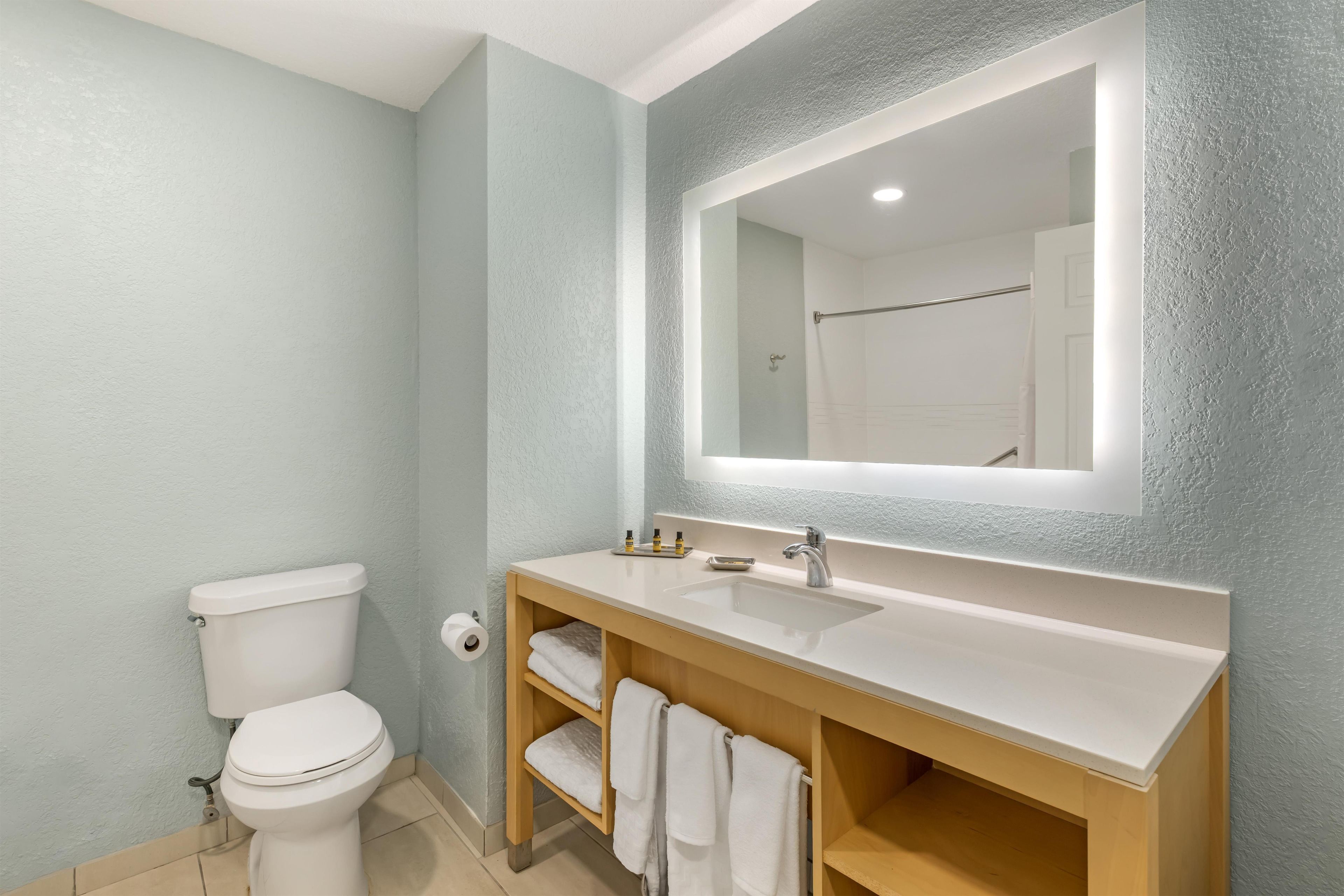 A bathroom with a white toilet, a sink with a mirror above it, and a towel rack with towels.
