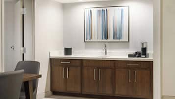 A modern kitchen with wooden cabinets, a white countertop, and a framed abstract painting above the sink.