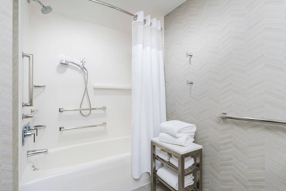 Ein modernes Badezimmer mit Badewanne, Dusche und Handtuchhalter.