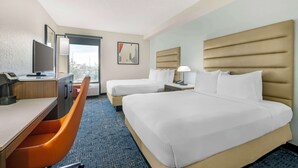 A hotel room with two beds, a desk, a chair, and a television. - Best Western Plus Universal Inn (Orlando)
