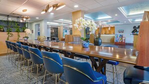 A conference room with a long table, blue chairs, and a vase of white orchids. - Best Western Plus Universal Inn (Orlando)