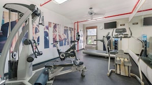 A gym with cardio machines, a treadmill, and a wall with fitness posters. - Best Western Plus Universal Inn (Orlando)