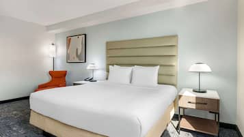 Une chambre d’hôtel avec un grand lit, une table de chevet, une chaise et une lampe fixée au mur.