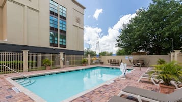 Una piscina al aire libre, sombrillas, sillones reclinables de piscina