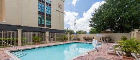 A swimming pool with lounge chairs and a building in the background.