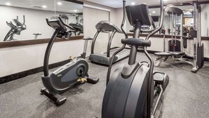 Un gimnasio con cintas de correr, elípticas y equipo de pesas.
