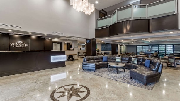 Un vestíbulo amplio con una mesa de recepción, sofás de cuero y un gran diseño de piso con motivos de estrellas.