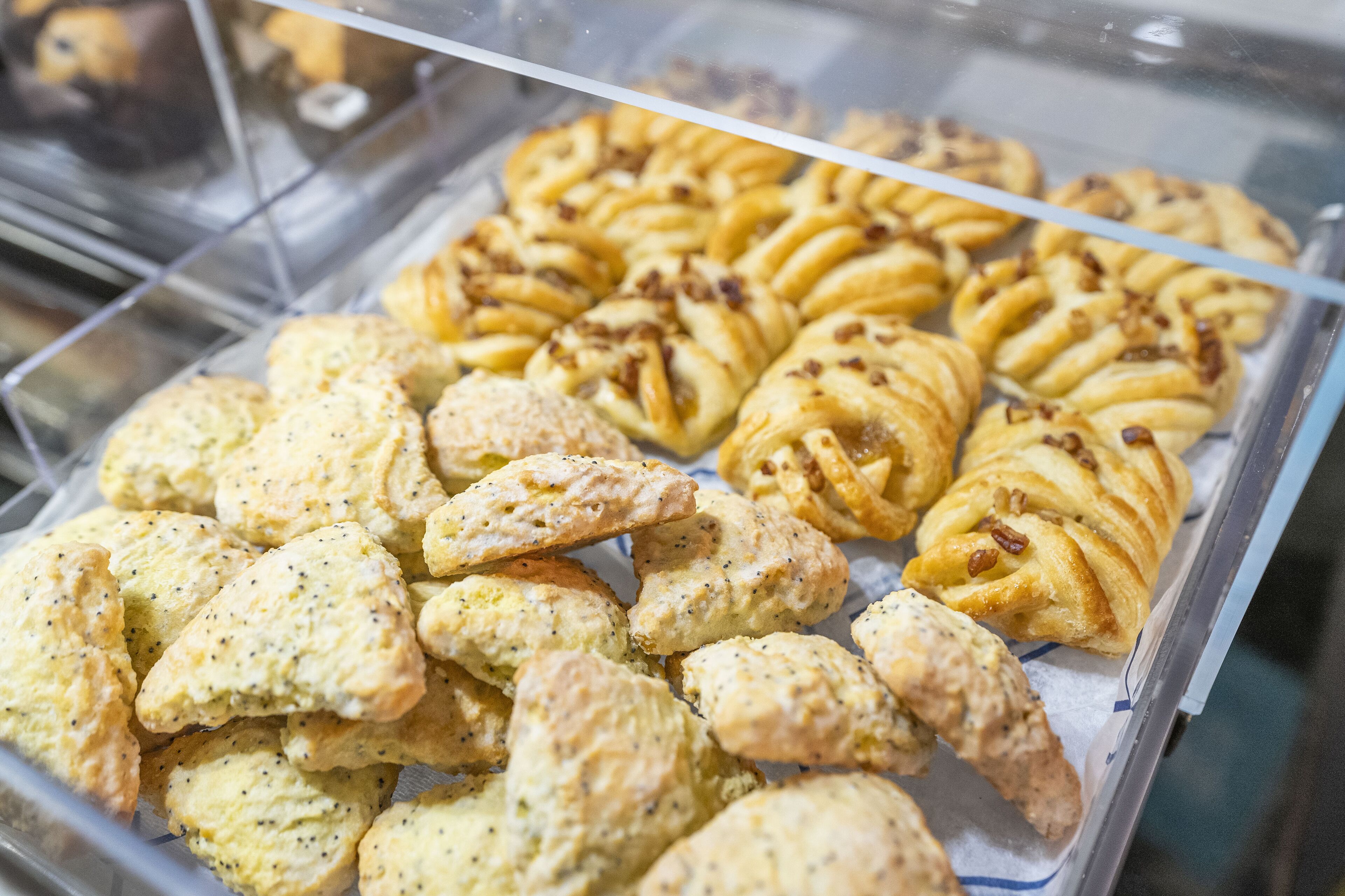 En bagerdisk fyldt med et udvalg af bagværk, herunder kager og scones.