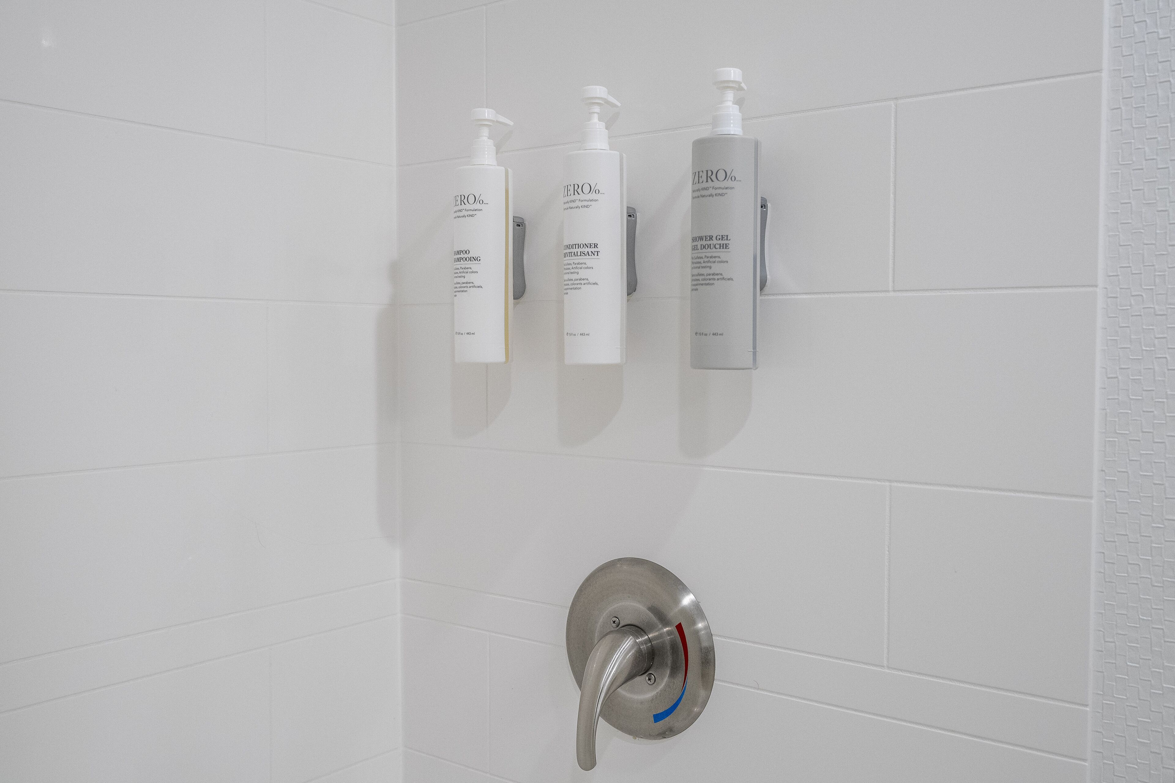 A bathroom with three white bottles labeled "ZERO" on a tiled wall.