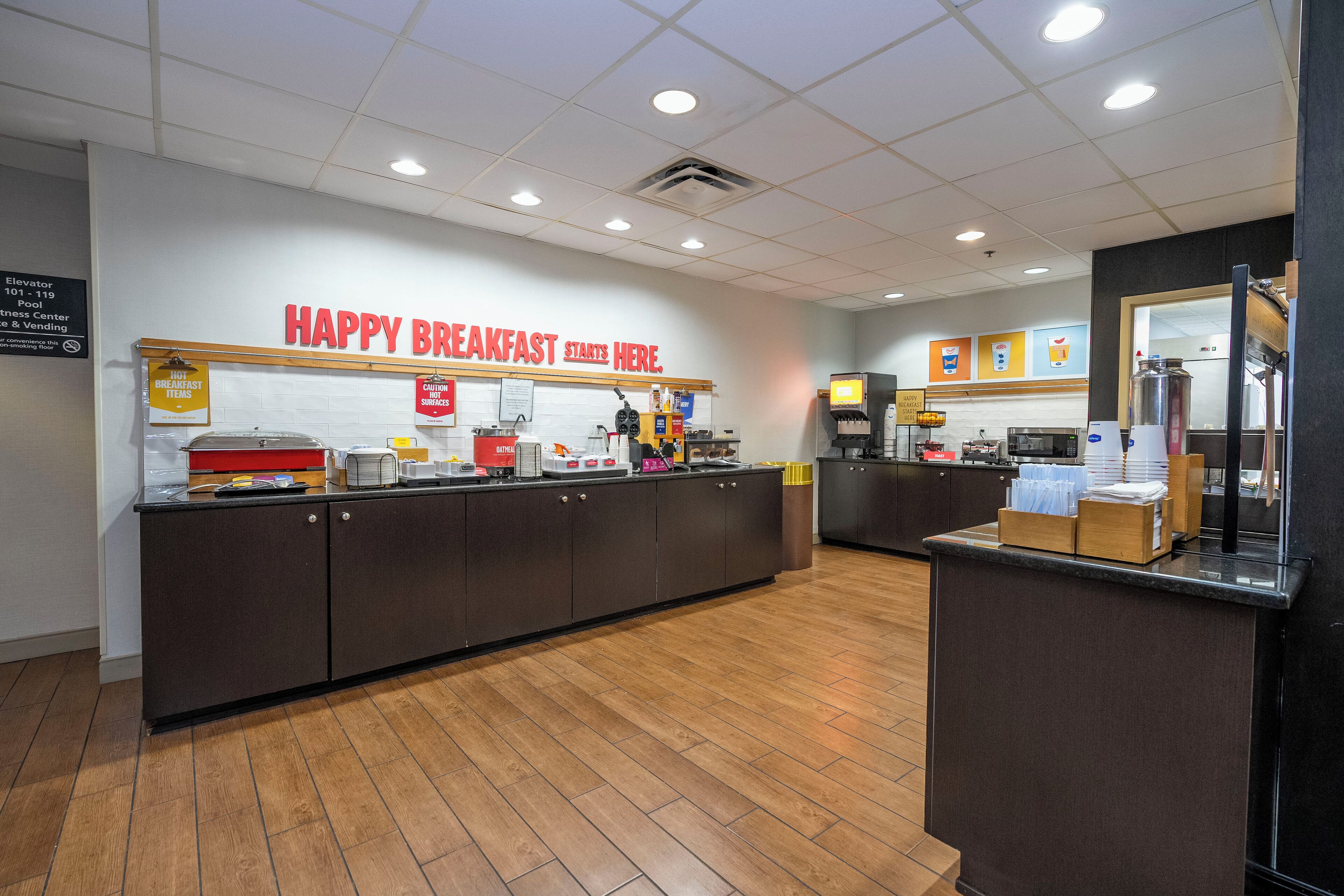Ein Frühstücksbereich mit einer Theke, Küchengeräten und einem Schild mit der Aufschrift 'HAPPY BREAKFAST STARTS HERE'.