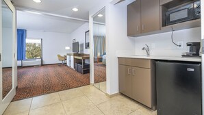 Una cocina compacta con microondas, refrigerador y un pequeño comedor con mesa y sillas.