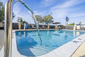A swimming pool with clear blue water, a metal handrail, and a sign indicating a pool area.