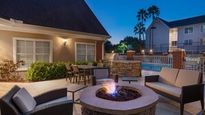 Une terrasse extérieure avec un foyer en pierre, des meubles en osier et un espace piscine.