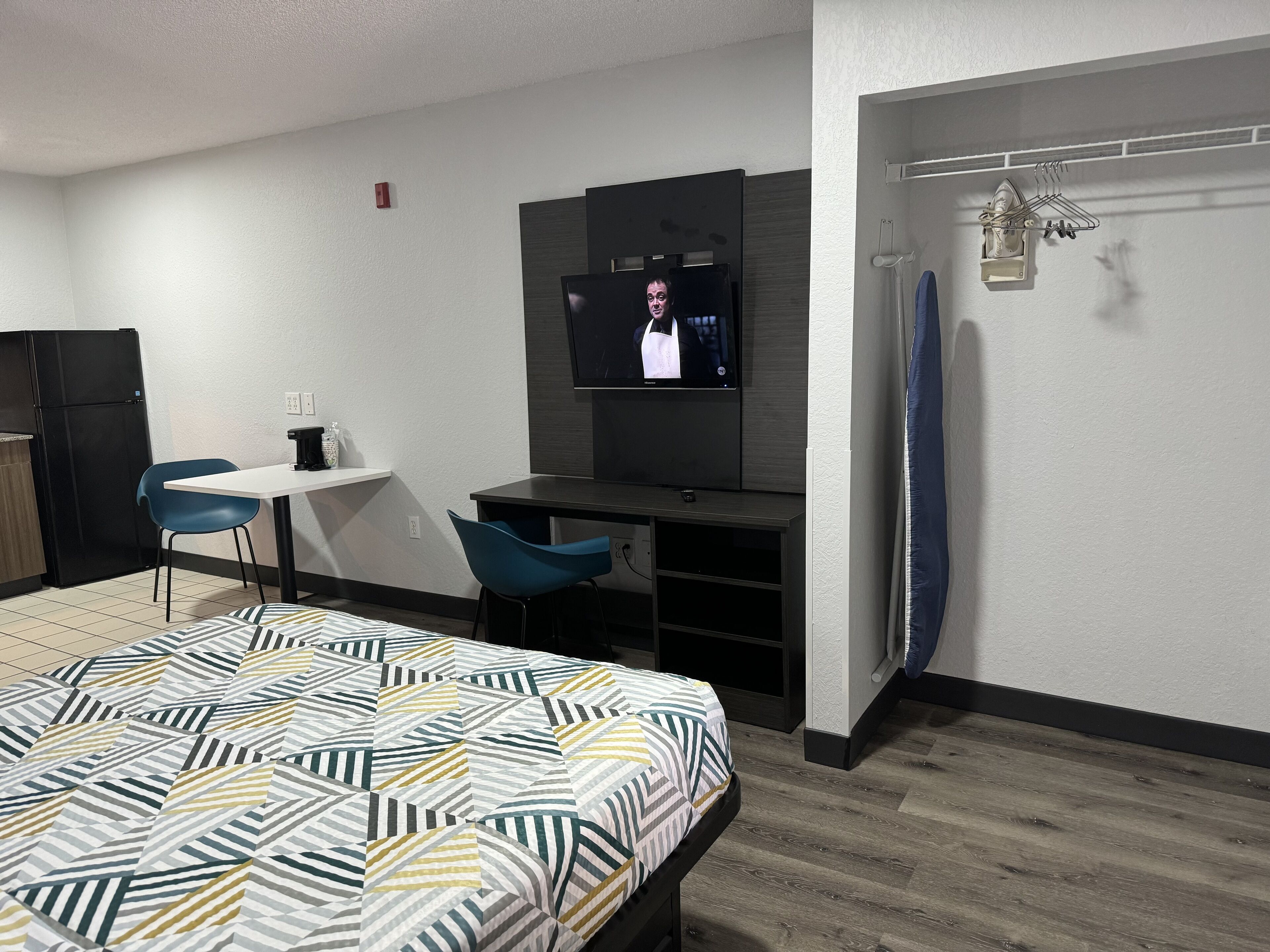 Une chambre d’hôtel comprenant un lit, un bureau avec une chaise, une télévision et un espace douche.