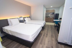 Een hotelkamer met twee bedden, een kitchenette en een kleine eethoek.