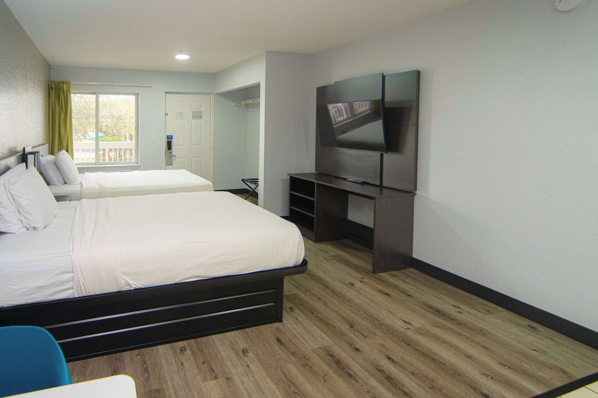 A hotel room with two beds, a TV, and a balcony with a view.
