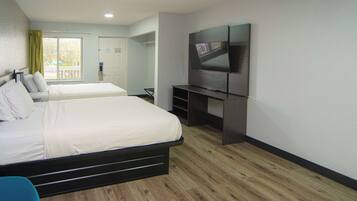 A hotel room with two beds, a TV, and a balcony with a view.