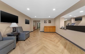 A hotel lobby with a reception desk, seating area, and a TV mounted on the wall. - Extended Stay America Suites West Palm Beach Northpnt Corpor (West Palm Beach)