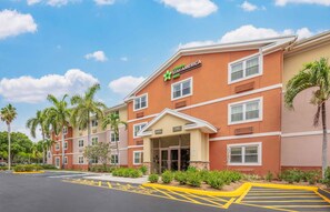 A StayAmerica hotel with a lobby entrance, palm trees, and a parking lot.