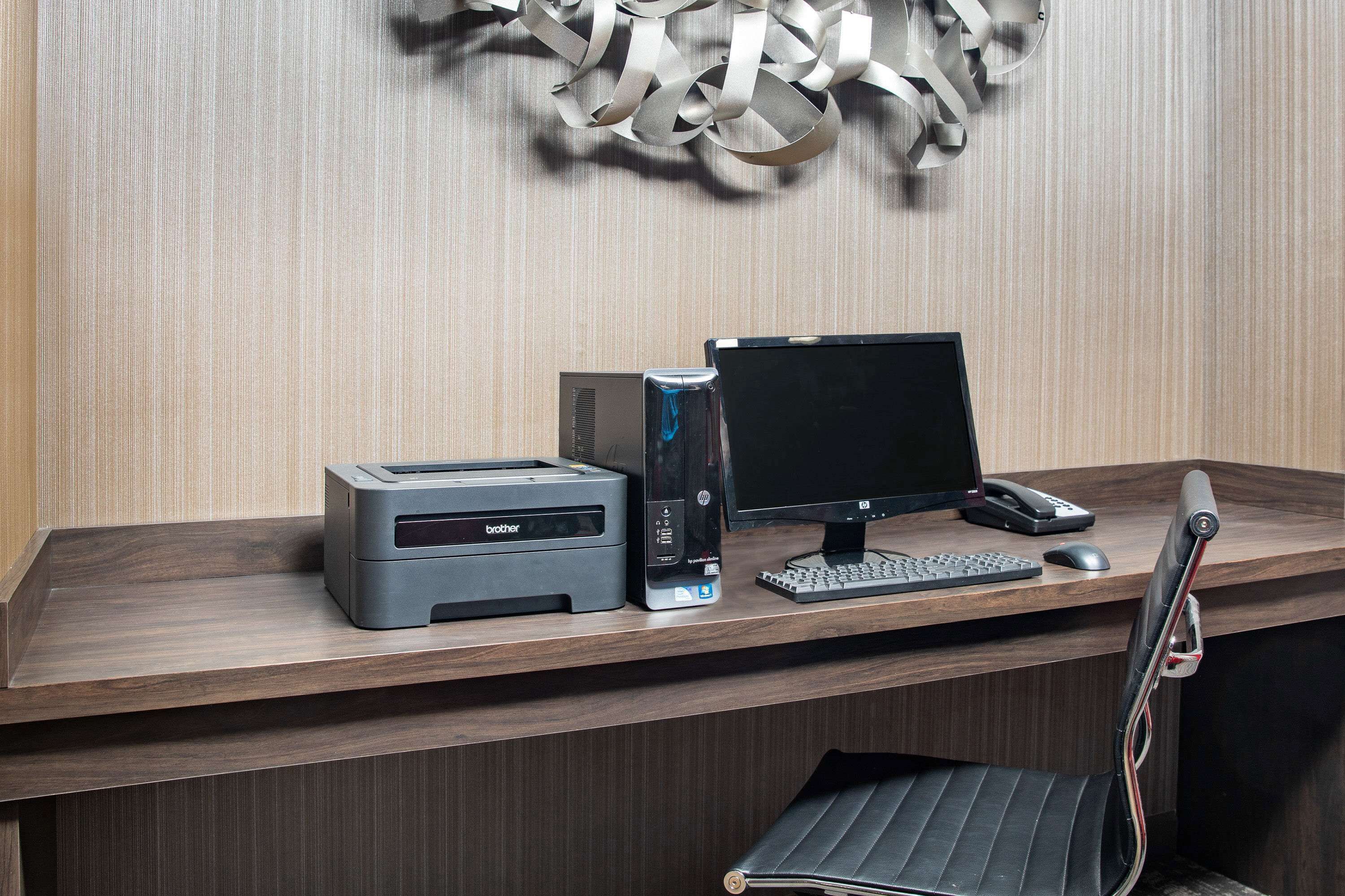 A wooden desk with a desktop computer, a printer, and a chair.