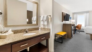 A hotel room with a large mirror, two sinks, a wooden desk, a chair, a bed, and a television. - Comfort Inn Blairsville Butternut Creek (Blairsville)