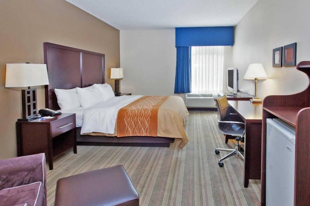 A hotel room with a bed, desk, chair, and a television.