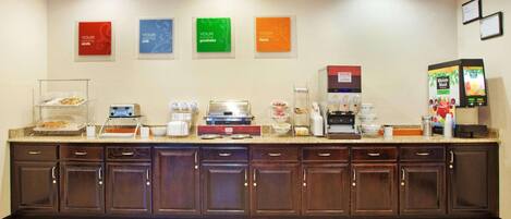 A hotel reception area with a counter, coffee machines, and a self-service beverage dispenser.