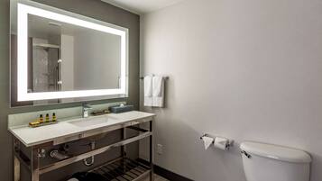 A modern bathroom with a large mirror, a sink, a toilet, and a towel rack.
