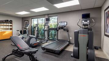 A gym with treadmills, elliptical machines, and a bench.
