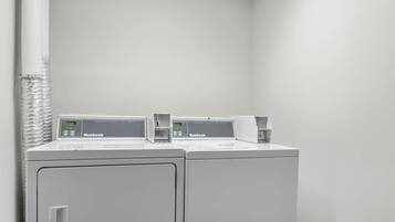A laundry area with two white washing machines and a dryer, both labeled 'Huebsch.'