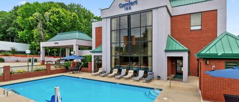 A Comfort Inn with a swimming pool, lounge chairs, and a brick facade.