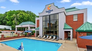 Ein Comfort Inn mit Swimmingpool, Liegestühlen und einer Ziegel-Fassade.