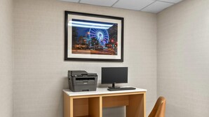A desk with a printer and monitor, a framed picture of a Ferris wheel, and a brown chair. - Comfort Inn Douglasville - Atlanta West (Douglasville)