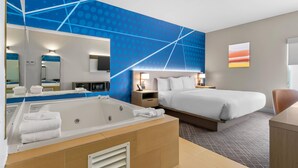 Ein modernes Hotelzimmer mit einem großen Bett, einem eigenen Badezimmer mit einer Badewanne, einem großen Spiegel und Blick auf den Sonnenuntergang.