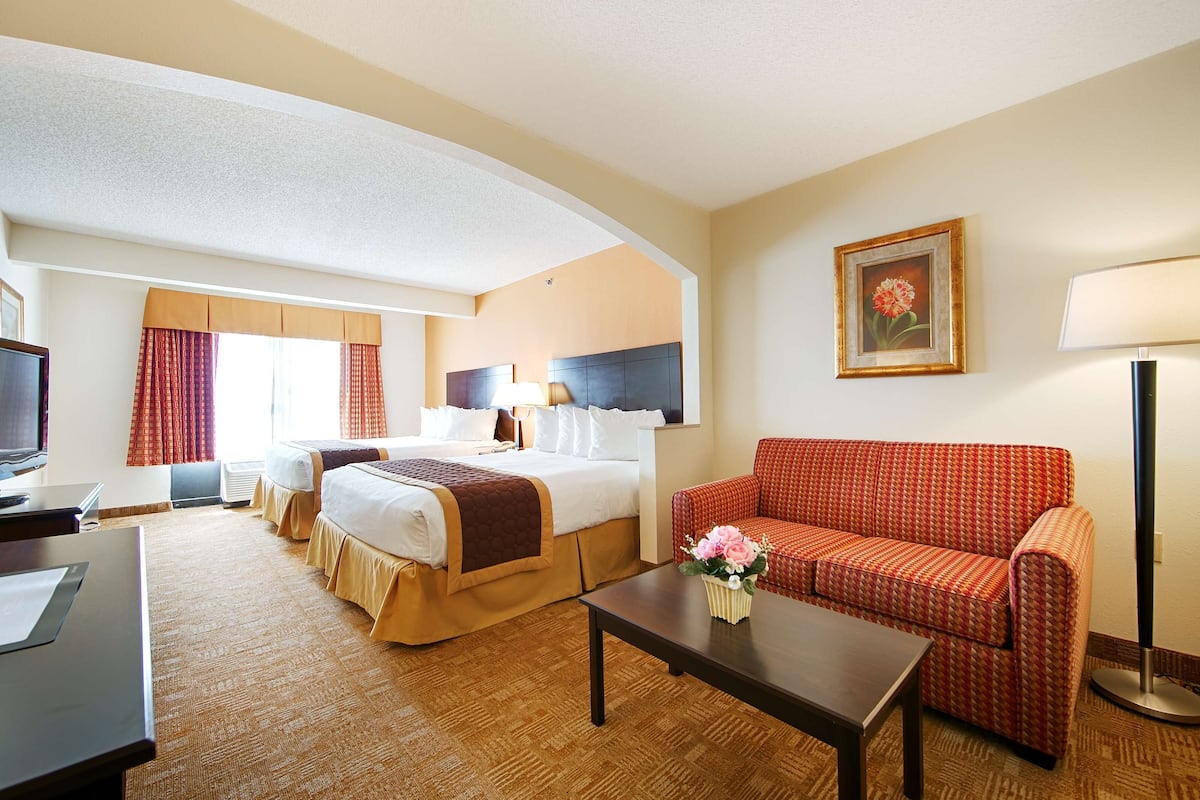 A hotel room with a bed, a sofa, a desk, and a TV.