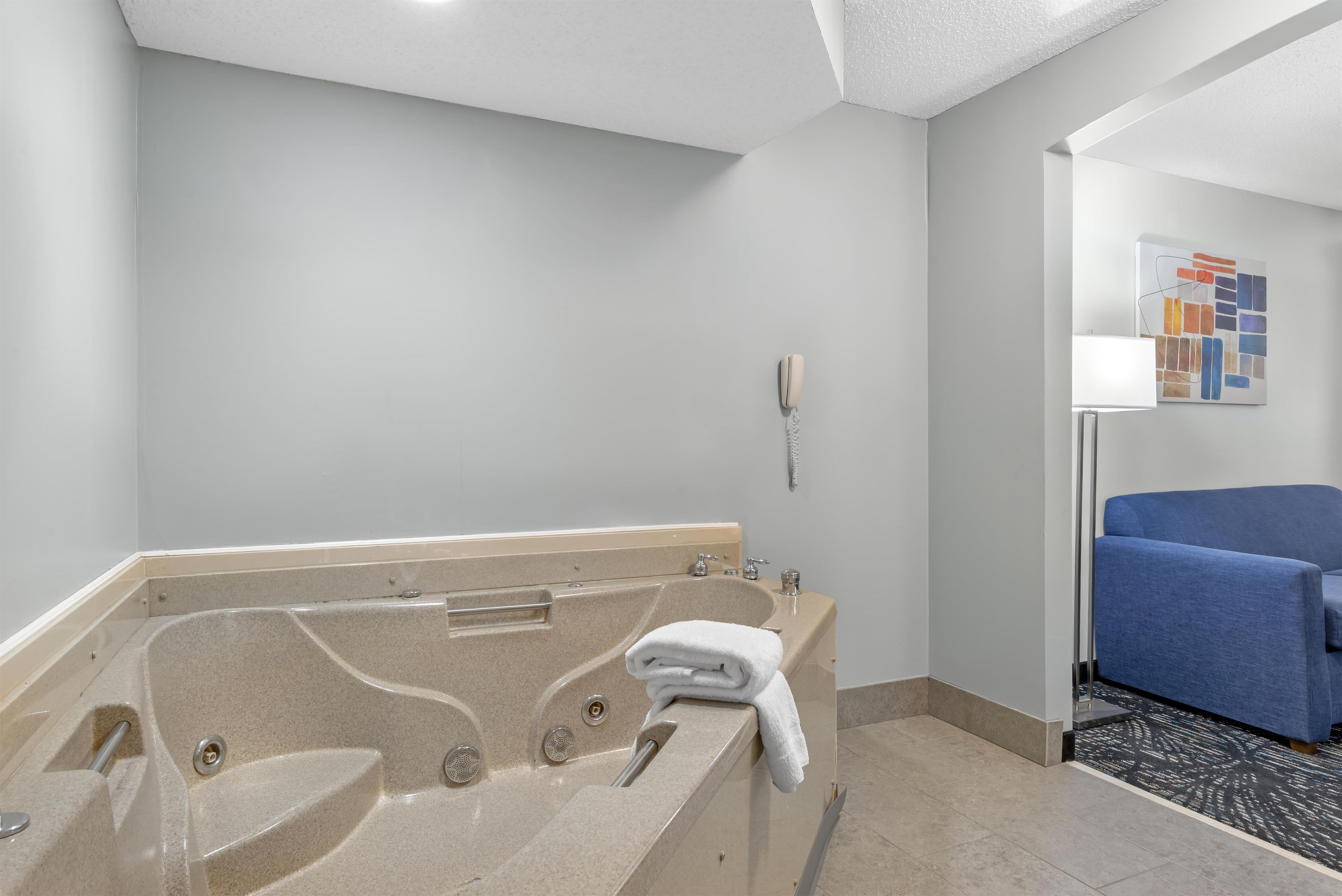 A modern bathroom with a freestanding bathtub, a towel, and a wall-mounted telephone.