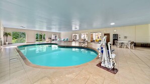Ein Innenpool mit klarem, blauem Wasser, umgeben von gefliesten Böden und einer Decke mit eingelassener Beleuchtung.
