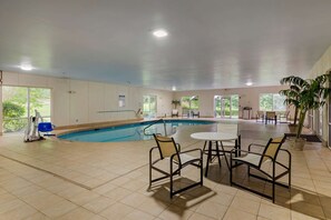 Relax by the pool in a serene indoor oasis with a rectangular pool, comfortable seating area, and natural light pouring in.