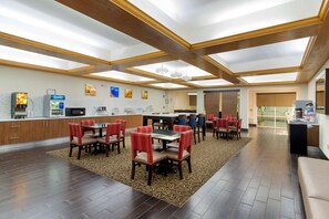 Experience the hotel's inviting lobby, featuring a high ceiling, dining tables, and artwork.