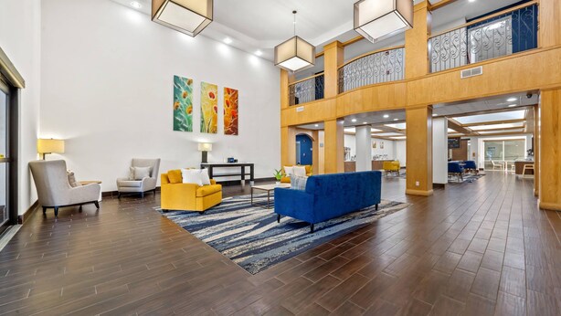 Eine geräumige Lobby mit hoher Decke, Holzböden und einem blauen Sofa. Zwei Sessel und ein gelbes Sofa stehen dort. Die Wände sind mit abstrakter Kunst versehen.