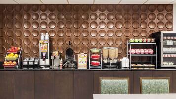 A breakfast bar with a variety of food items and beverages, including fruits, cereals, and packaged goods.