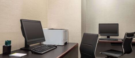 A modern office space with two desks, each equipped with a computer monitor, keyboard, and printer.