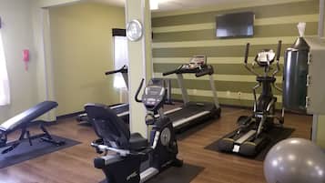 A gym with treadmills, an elliptical, a stationary bike, a bench, and an exercise ball.