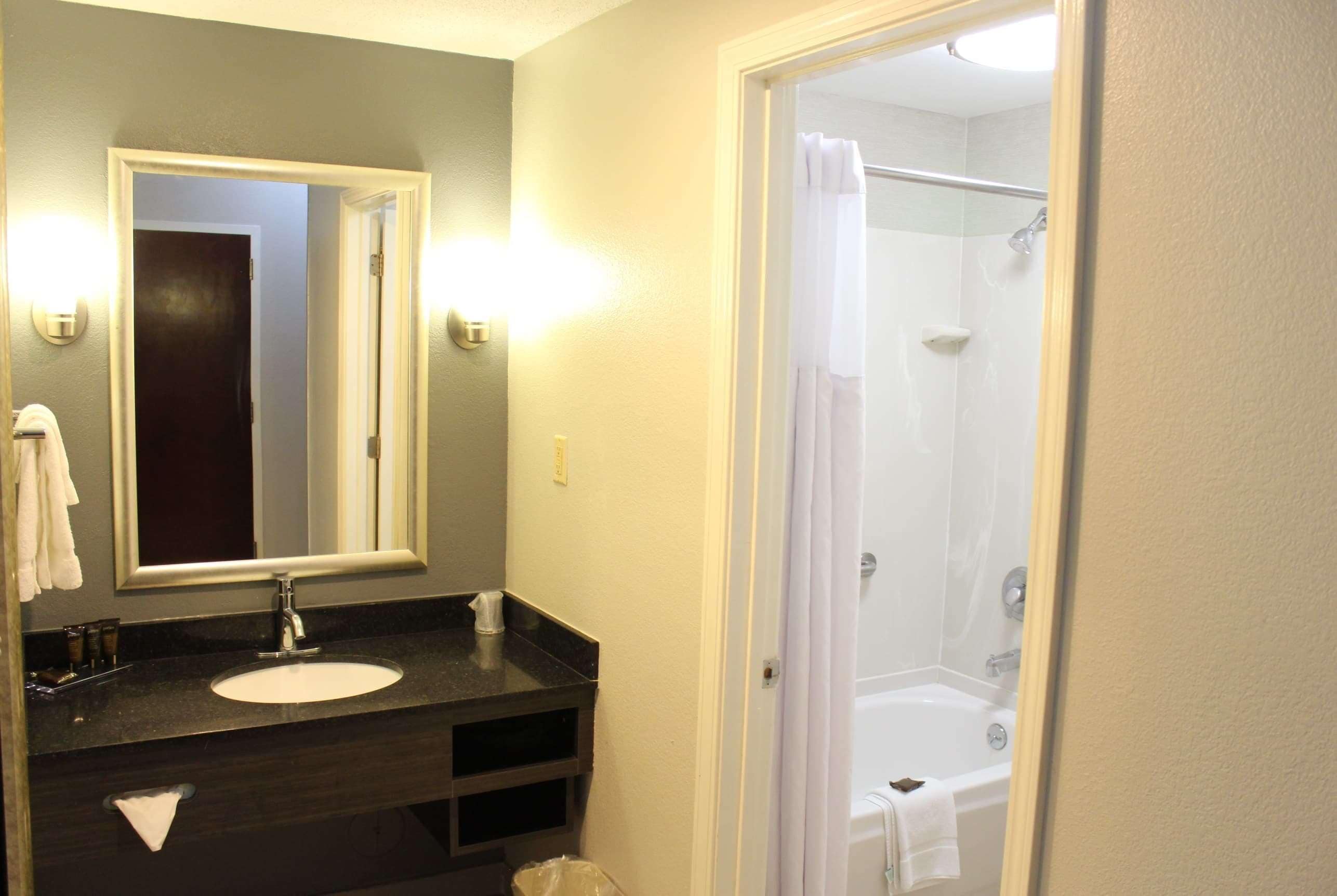 A bathroom with a sink, mirror, and shower area.