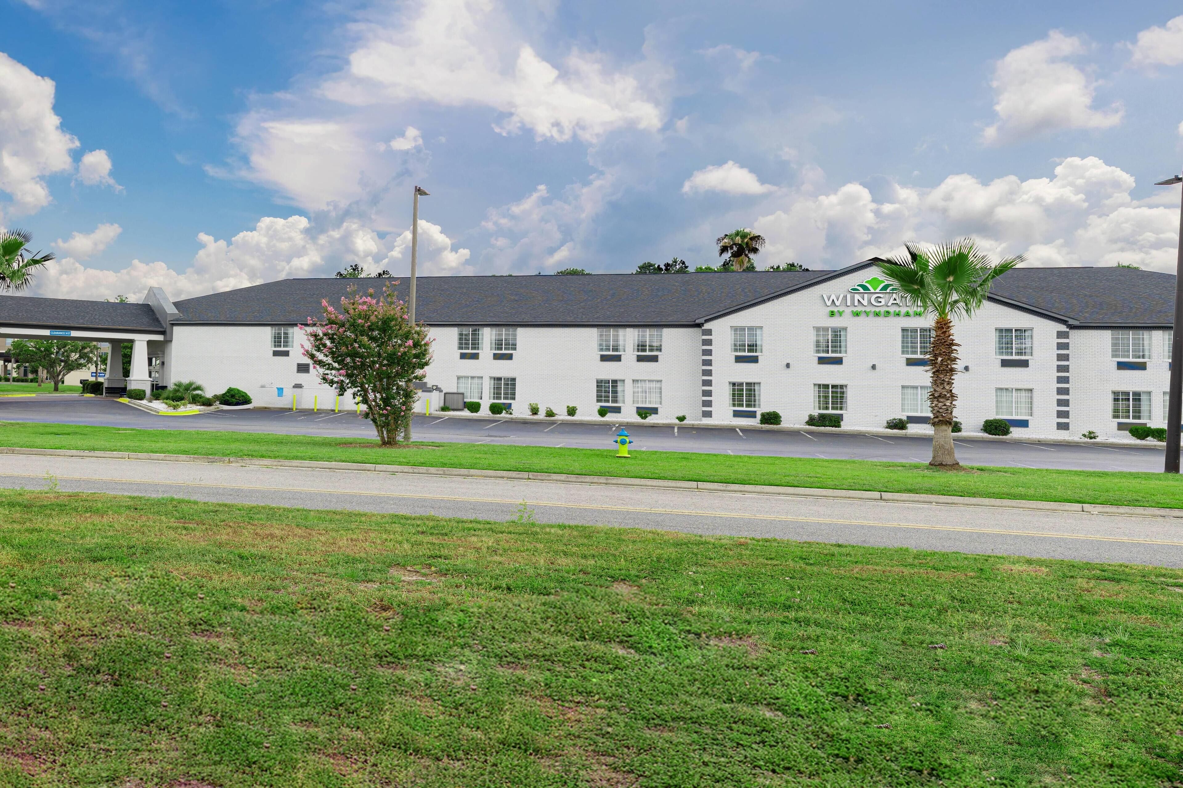 A hotel with a white exterior, multiple windows, and a parking lot.