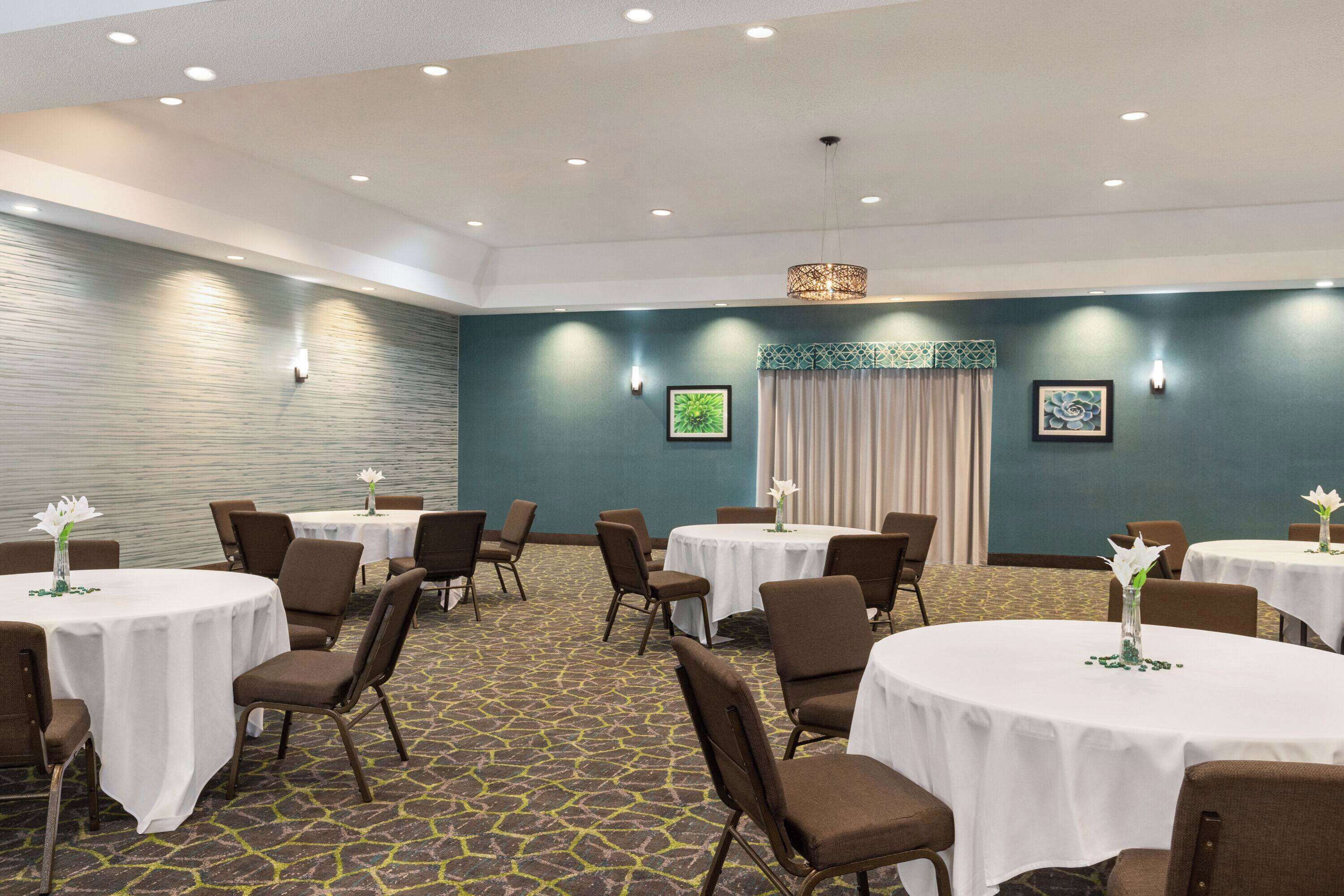 A conference room with multiple round tables, chairs, and a patterned carpet.