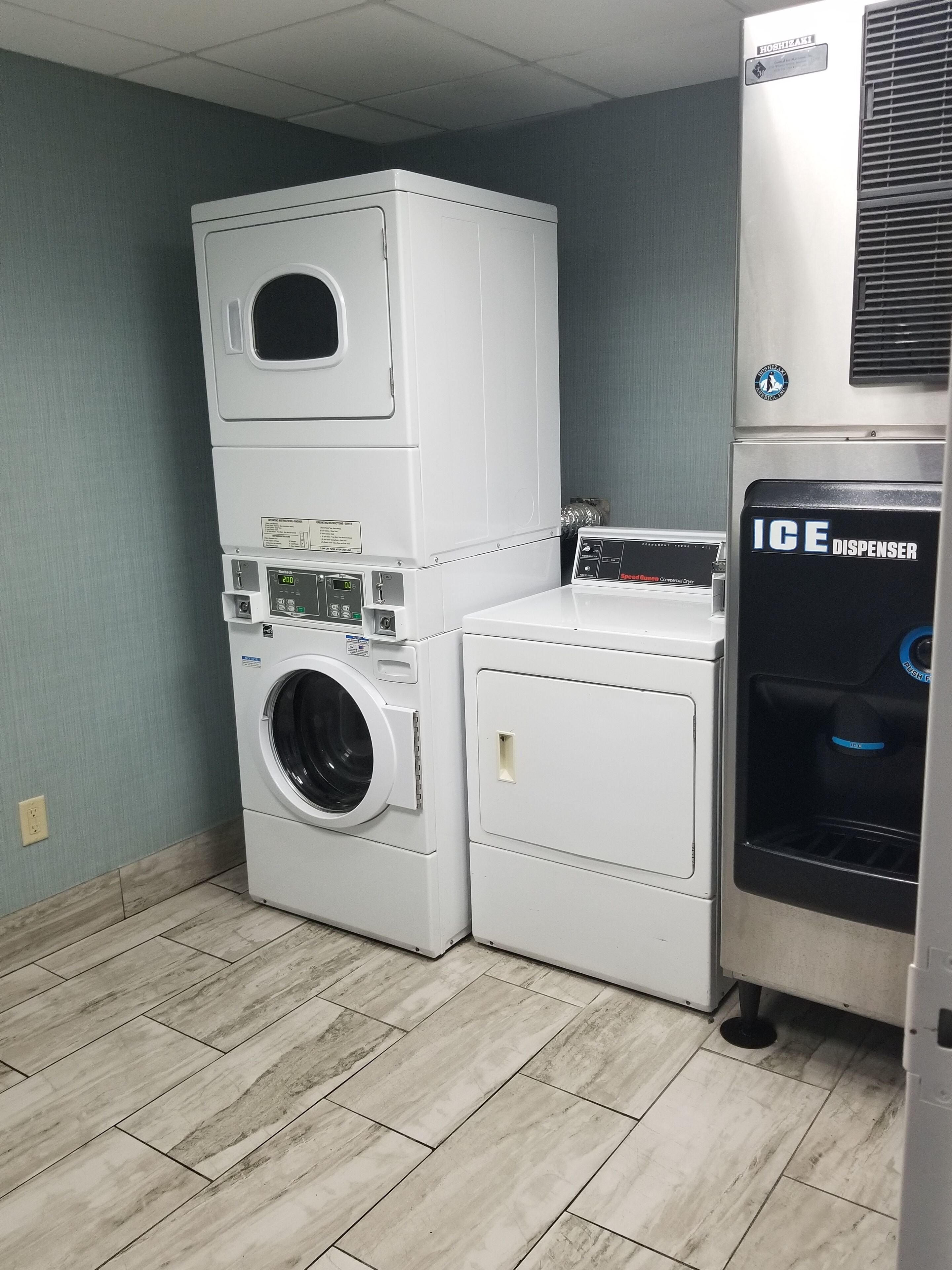 A laundry room with stacked washers and dryers, a water heater, and an ice dispenser.