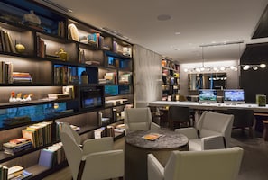 A modern library with bookshelves, a round table, and multiple computer monitors. - Hyatt Centric Chicago Magnificent Mile (Chicago)