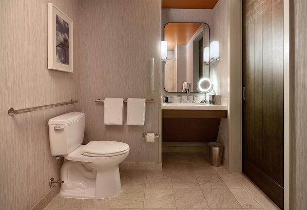 Un baño moderno con inodoro, lavabo, espejo y toallero.
